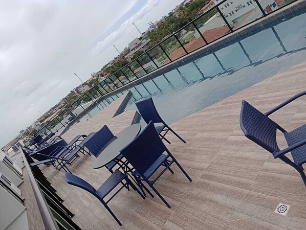 A rooftop terrace with a swimming pool, outdoor seating, and a view of the surrounding buildings. - Flat no centro de Porto de Galinhas  (Ipojuca)
