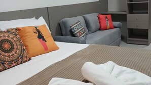 A hotel room with a bed, grey sofa, and a wardrobe. - Flat no centro de Porto de Galinhas  (Ipojuca)