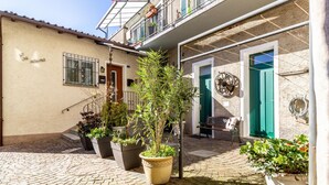 A courtyard with potted plants, a staircase, and a building with a sign 'Ca Socina'. - Tiny Home Lugano South   Parking & Comfort (Grancia)