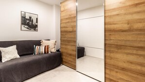 A modern room with a grey sofa, a wooden wardrobe, and a framed picture on the wall. - Tiny Home Lugano South   Parking & Comfort (Grancia)
