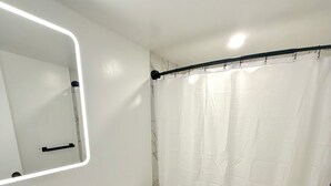 Un baño con lavamanos, inodoro y cortina de ducha blancos.