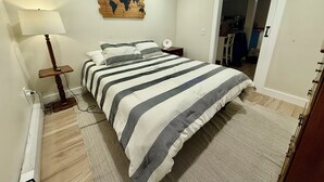 Un dormitorio con cama, mesita de noche, lámpara y un mapa del mundo en la pared.