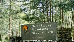 Een hond zit voor een bord met daarop Great Smoky Mountains National Park.