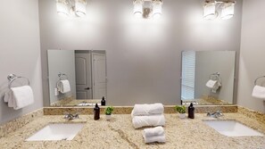 Ein Badezimmer mit zwei Waschbecken, einem großen Spiegel und drei Deckenleuchten.