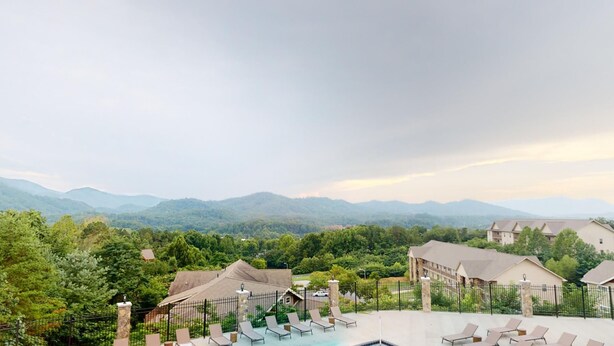 A hotel with a pool area, lounge chairs, and a view of mountains. - NEW 2 Bedroom Condo in Pigeon Forge- Unit 4, NEW 2 Bedroom Modern Mountain Escape - Club House Unit (Pigeon Forge)