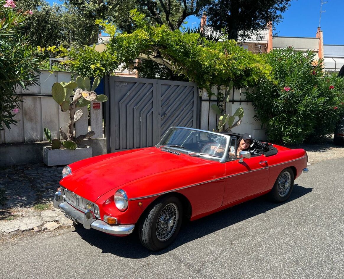 Une voiture rouge décapotable est garée dans la rue.