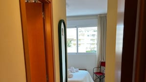 A hotel room with a bed, a chair, a window with curtains, and a view of buildings outside. - Playasol in Denia With 3 Bedrooms and 2 Bathrooms (Denia)