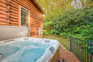 Eine Holzblockhütte mit Whirlpool im Vordergrund und einer Holzterrasse.