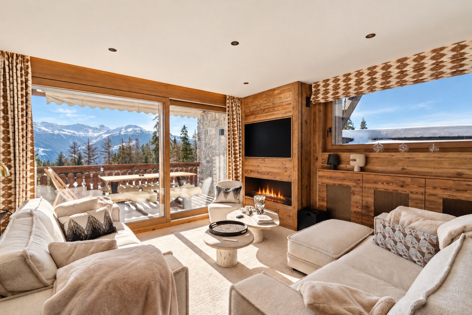 Ein gemütliches Wohnzimmer mit Kamin, bequemen Sitzmöglichkeiten und einem großen Fenster mit Blick auf eine Berglandschaft.