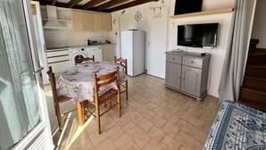 A compact kitchen with wooden beams, a dining table with chairs, a washing machine, and a refrigerator. - Holiday house, 2 bedrooms,4 people, airco in living room, at only 300m from the beach of... (PORTIRAGNES)
