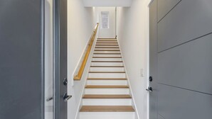 A modern staircase with wooden steps and a handrail, leading to a landing with a small window. - Spacious Studio Suite, Downtown Durham (Durham)