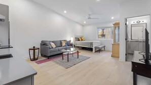 A modern living room with a sofa, a coffee table, a bed, and a TV. - Spacious Studio Suite, Downtown Durham (Durham)