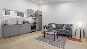 A modern kitchen with grey cabinets, a microwave, and a built-in oven. - Spacious Studio Suite, Downtown Durham (Durham)