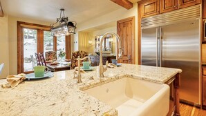 A kitchen with a large island, stainless steel appliances, wooden cabinets, and a chandelier. - Luxury Ski-In/Ski-Out Empire Pass Retreat | Private Hot Tub | Sleeps 12 (Park City)
