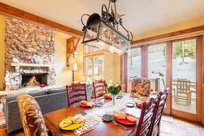 A dining area with a stone fireplace, wooden dining table, and chairs.