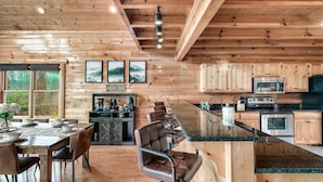 A wooden cabin interior with a dining area, kitchen, and seating. - Top of the World: Summer deals-Theater-hot tub-arcade games-million dollar views (Sevierville)