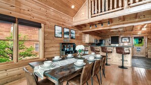A wooden cabin interior with a dining area, kitchen, and a balcony. - Top of the World: Summer deals-Theater-hot tub-arcade games-million dollar views (Sevierville)