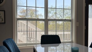Ein Essbereich mit großem Fenster, einem weißen Tisch und blauen Stühlen.