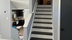 Eine Treppe führt zu einer zweiten Etage, im Hintergrund ist eine Küche erkennbar.