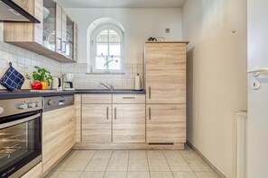 A modern kitchen with wooden cabinets, a built-in oven, and a window with a view of the outdoors. - Störtebekerstraße 14 - Apartment 6 - Comfortable vacation apartment with terrace and (Zingst (Ostseeheilbad))