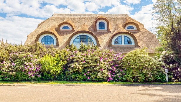 Una casa con un diseño arquitectónico único, con ventanas redondeadas y fachada texturizada.