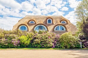 Ett hus med en unik arkitektonisk design, kännetecknat av rundade fönster och en fasad med en intressant yta.