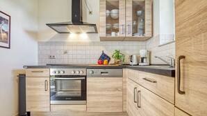 Una cocina moderna con armarios de madera, horno empotrado y cafetera.