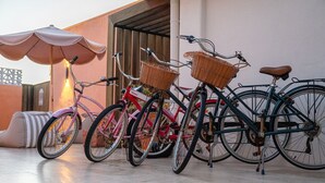 Une rangée de vélos est garée devant un bâtiment dont le sol est recouvert de carreaux et qui possède une porte en bois.