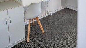 Une pièce moderne et blanche, comprenant un bureau, une chaise, un téléviseur, un miroir décoratif et une petite plante.