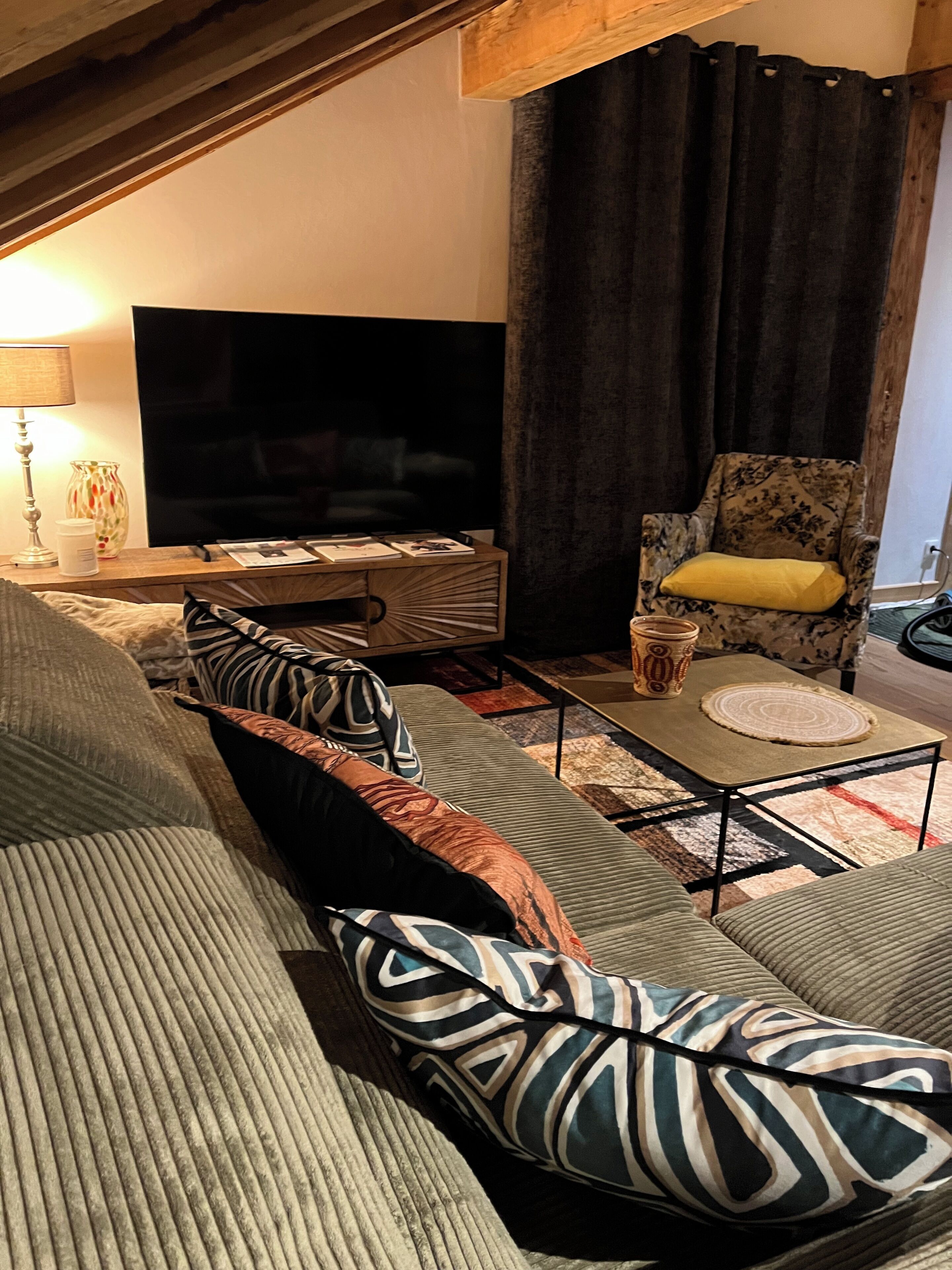 Ein gemütliches Wohnzimmer mit Sofa, Couchtisch, Fernseher und Sessel.