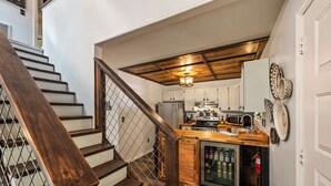 A kitchen with wooden cabinets, a stainless steel refrigerator, and a wooden island with a sink.