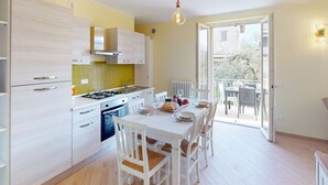 Eine moderne Küche mit weißen Schränken, einer gelben Spritzschutzleiste und einem Essbereich mit weißen Stühlen und einem Tisch.
