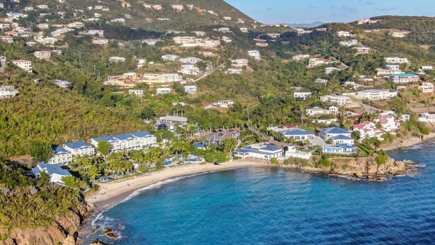 Une ville côtière dotée de propriétés en bord de mer, d’une végétation luxuriante et d’un paysage vallonné en arrière-plan.