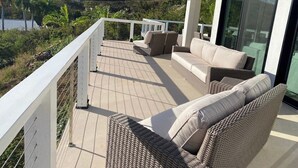 Un balcon doté de meubles en osier et offrant une vue sur une colline.