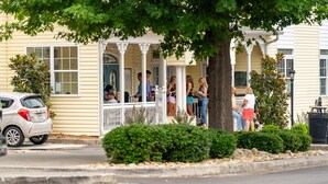 A row of yellow houses with a porch where people are gathered. - *Box Car*Downtown Blue Ridge|Southern Charm Suites (Blue Ridge)