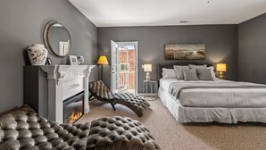 Una camera da letto con camino, un letto, una chaise longue e vista sull'esterno.