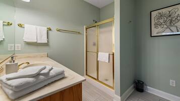 A bathroom with a vanity, a glass shower enclosure, and a framed floral artwork on the wall.