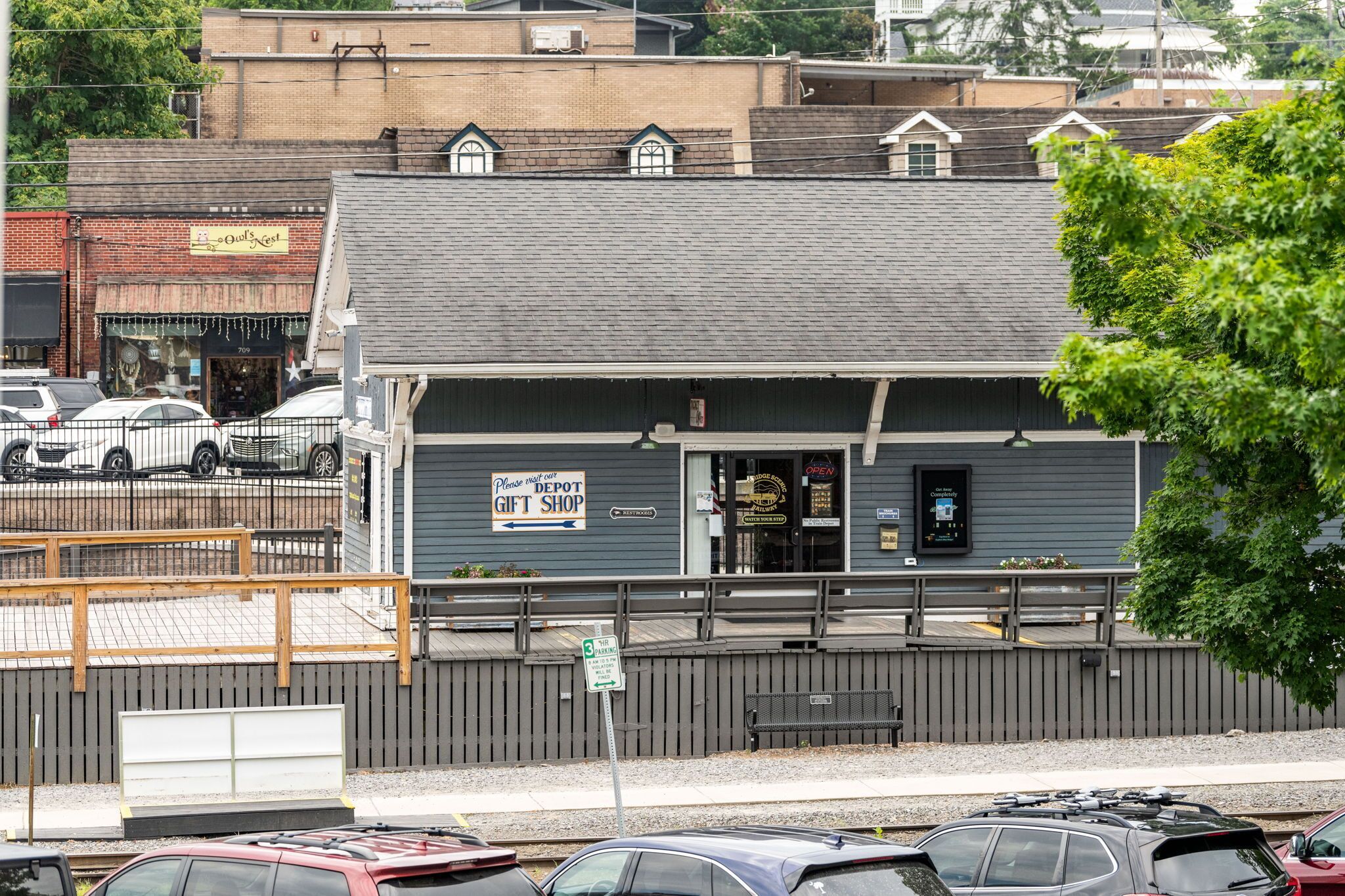 A building with a sign for a gift shop, a bench, and a fenced parking area.