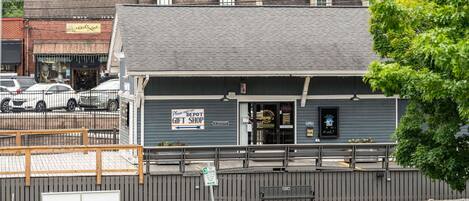 A building with a sign for a gift shop, a bench, and a fenced parking area.