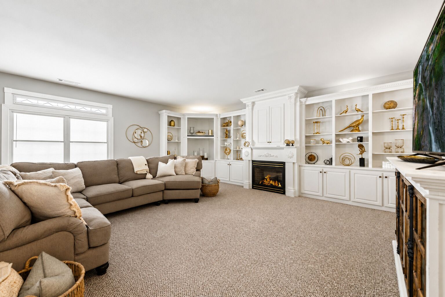 A living room with a sectional sofa, a fireplace, and built-in shelving with decorative items.