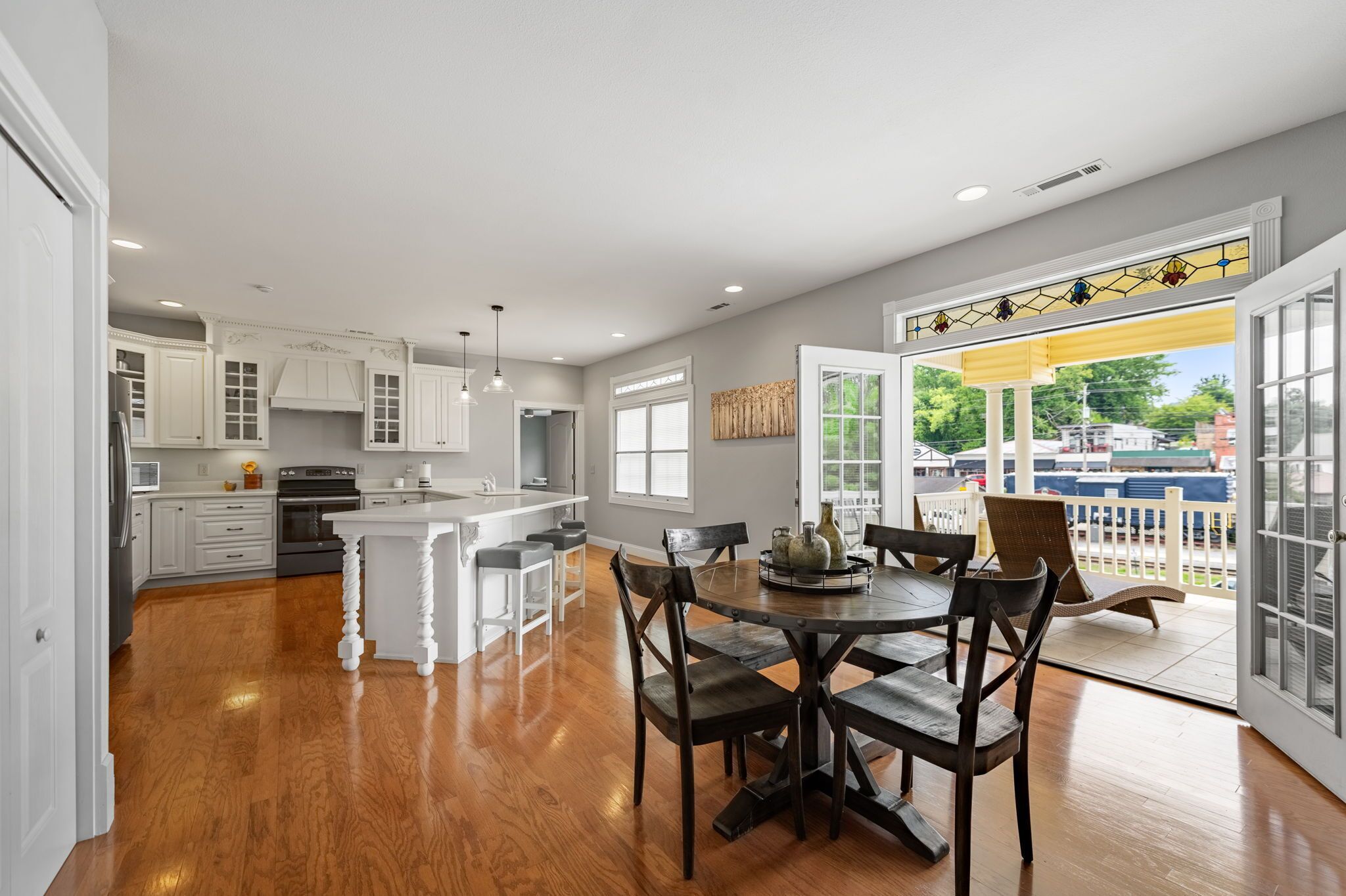 A spacious kitchen with white cabinetry, a central island, and a dining area with a table and chairs.