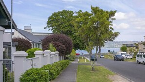 A residential street with houses, a sidewalk, and a road with cars. - 3 BR Holiday home - Steps to the lake and short, scenic stroll to town (Taupō)