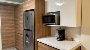A compact kitchen with a built-in refrigerator, a microwave, and a coffee maker on a marble countertop. - Beautiful, comfortable and relaxing house 15 min from Vineyards (El Sauzal)