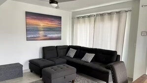 A modern living room with a sectional sofa, a grey ottoman, a wooden coffee table, and a ceiling fan. - Beautiful, comfortable and relaxing house 15 min from Vineyards (El Sauzal)