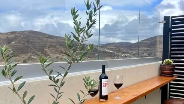 A balcony with a wooden bar, two stools, a bottle of wine, and glasses. - Beautiful, comfortable and relaxing house 15 min from Vineyards (El Sauzal)