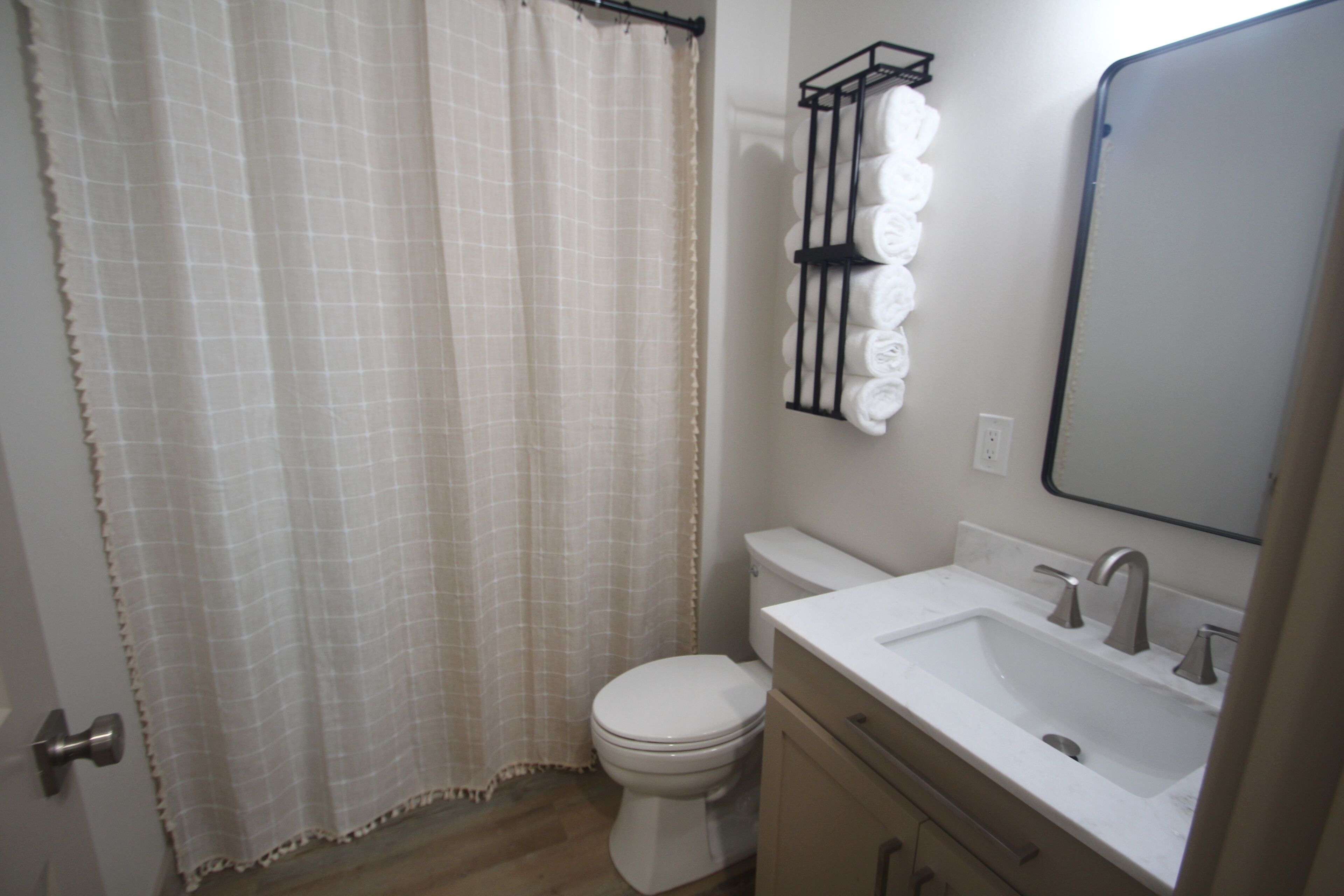 A bathroom with a toilet, sink, and mirror.