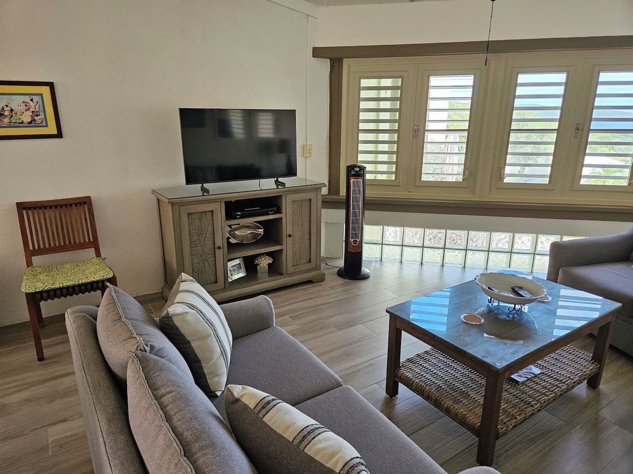 A living room with a sofa, a coffee table, a TV, and a window with blinds.