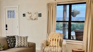 A living room with a sofa, armchair, round wooden coffee table, and a small side table. - Hilltop Harbor House (Granbury)