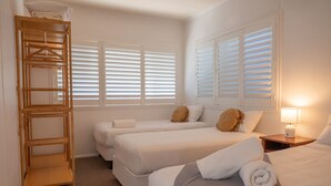 Ein Hotelzimmer mit zwei Betten, einem Holzregal und einer Nachttischlampe.
