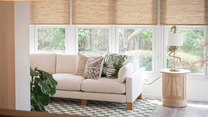 A room with a white sofa, checkered rug, and a rattan side table with a lamp. - Welcome to The Florida Rooms- Your Relaxing Retreat Near the Gulf! New Pool Spa! (Bradenton)